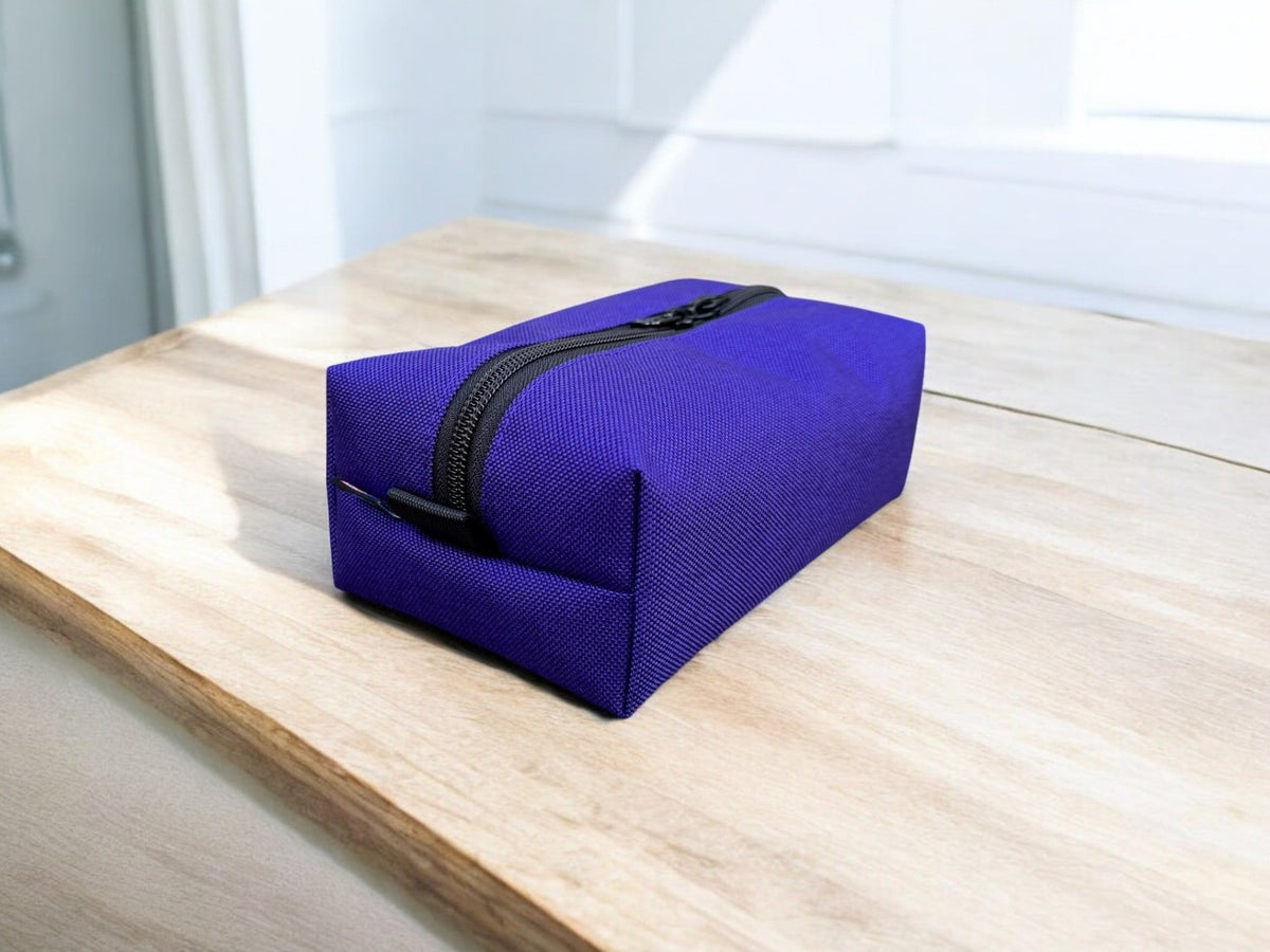 Blue toiletry bag with a black zipper on a wooden surface