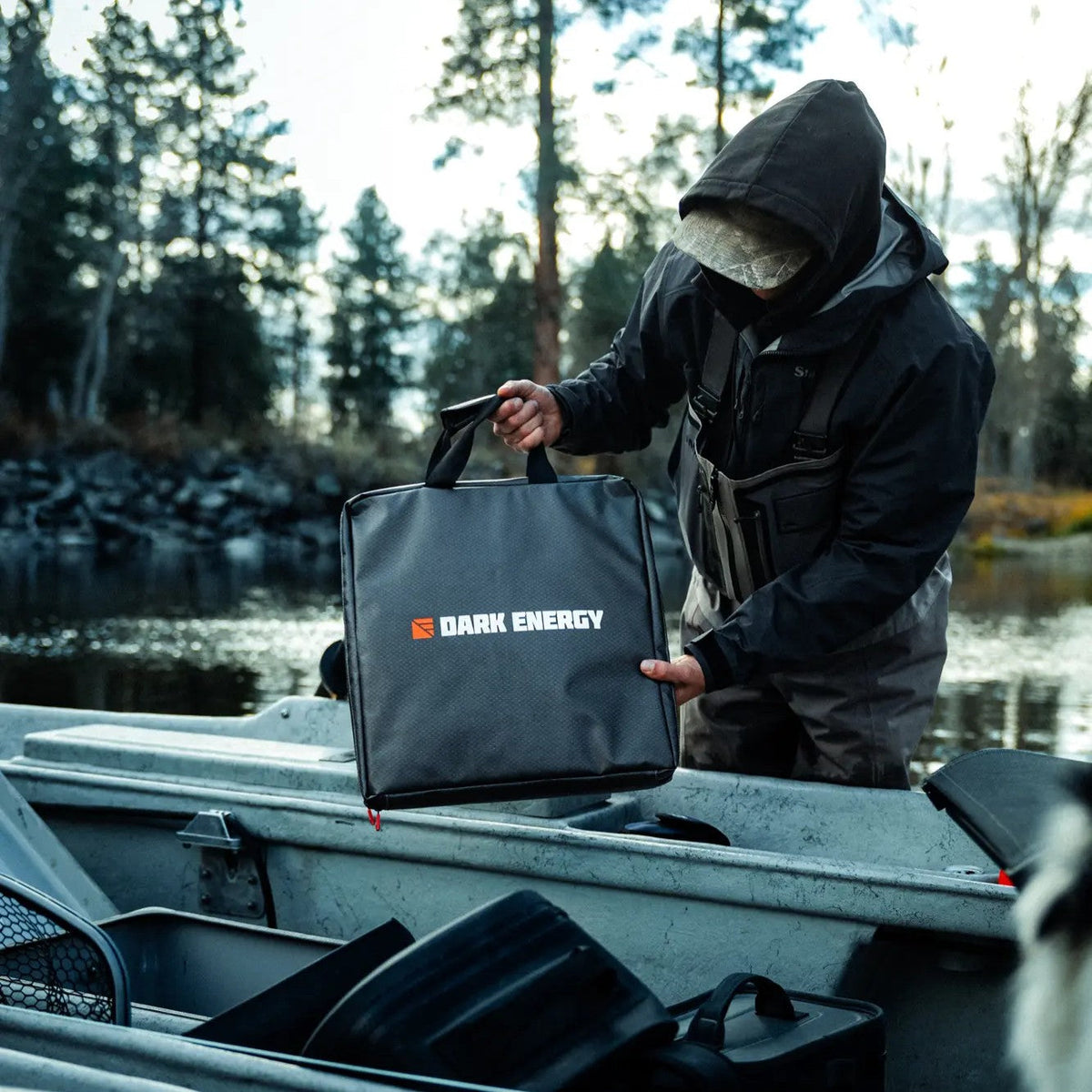 Person holding a 'Dark Energy' bag on a boat with a forest background