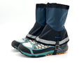 Pair of blue and black gaiters attached to hiking boots on a white background