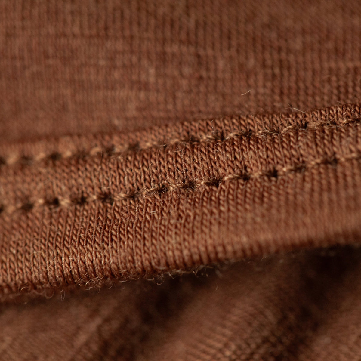 Close-up of a brown woven fabric with a stitched seam detail.
