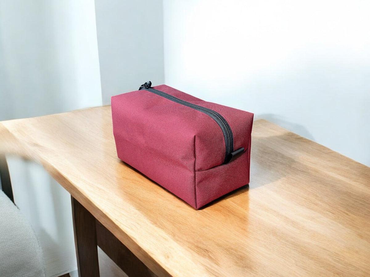 Red toiletry bag with black zipper on a wooden table