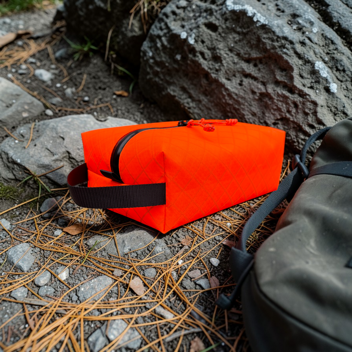 Orange bag with black straps on a rocky ground