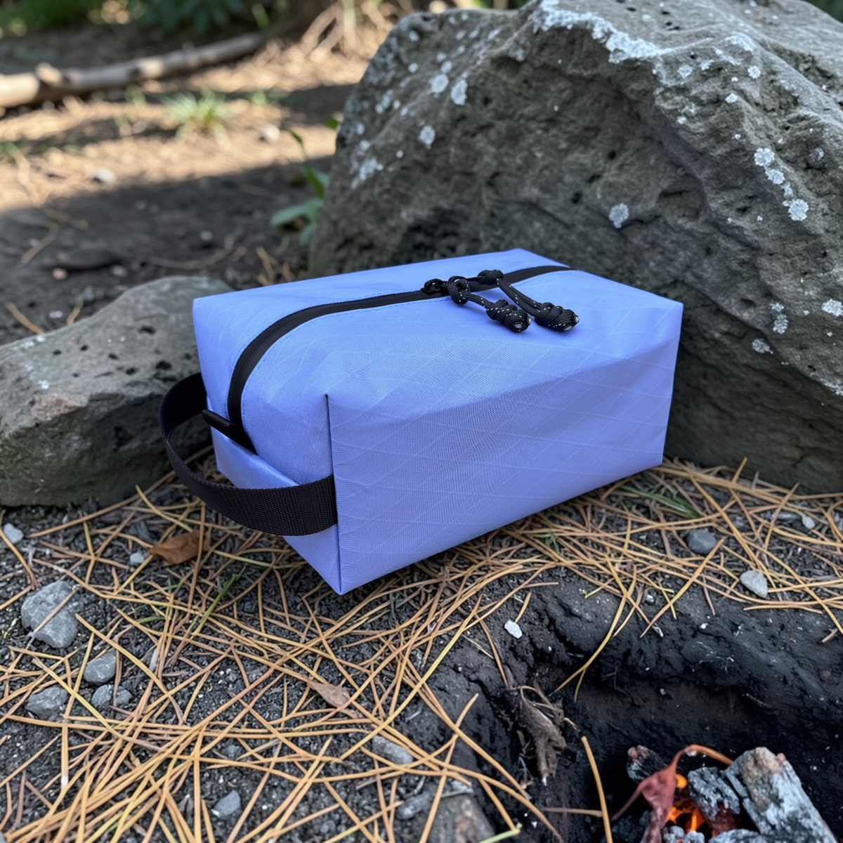 Purple rectangular pouch with black straps on a rocky ground