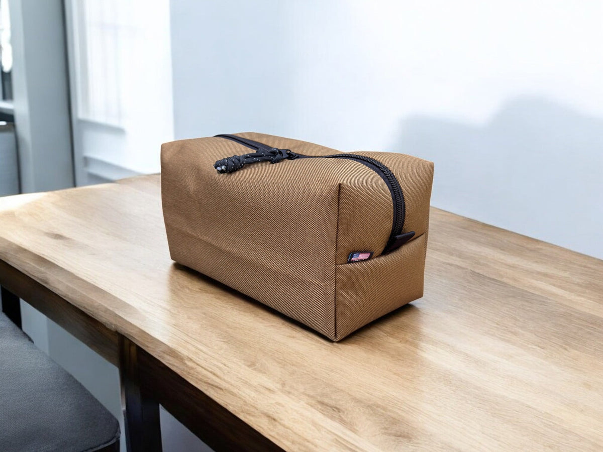 Brown toiletry bag with black zipper on a wooden surface