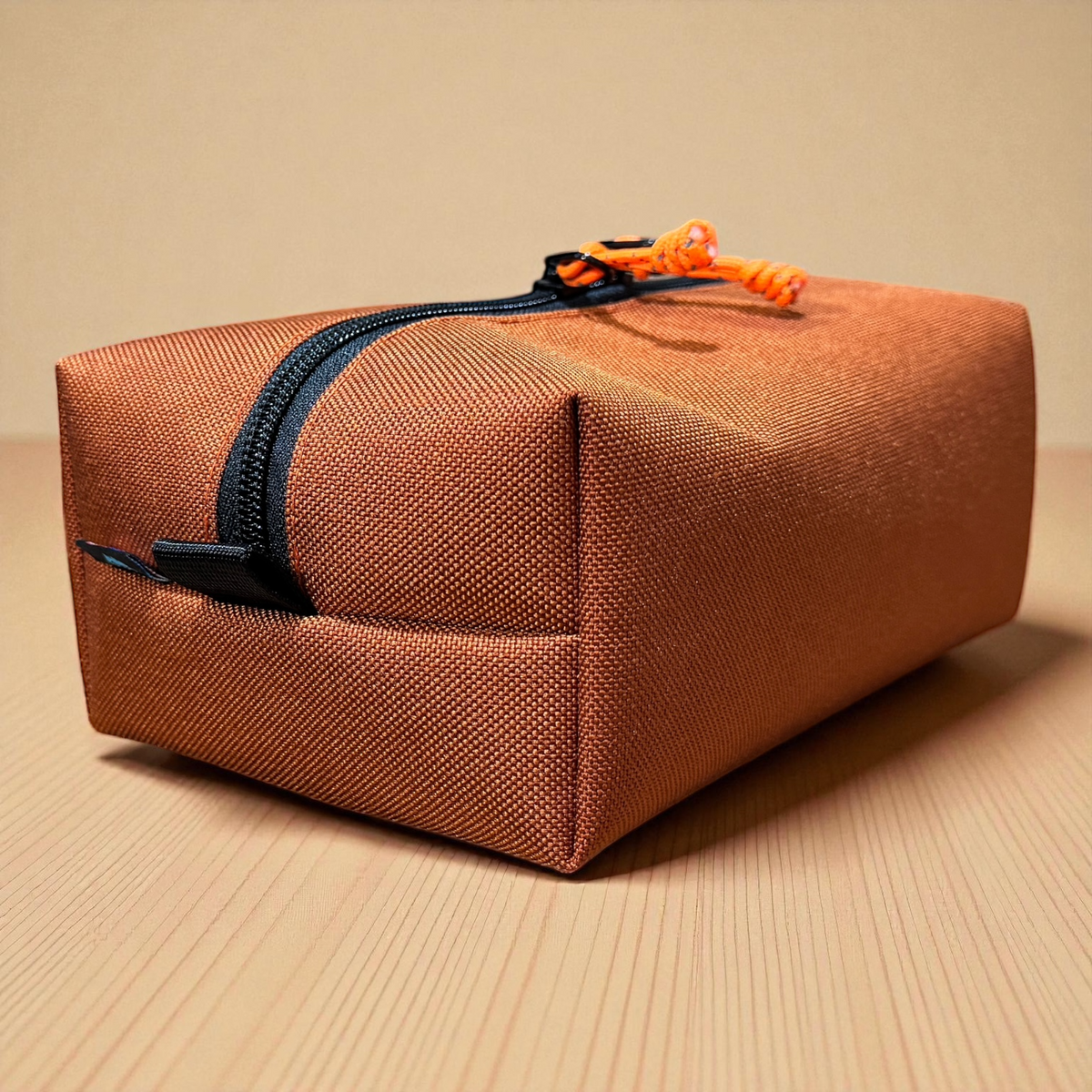 Brown rectangular pouch with a black zipper on a beige background