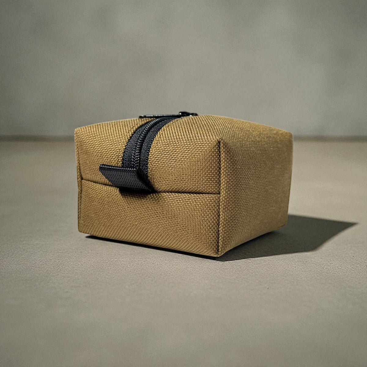 Brown woven rectangular box with a black zipper on a beige background
