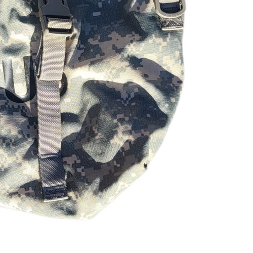 Close-up of a digital camouflage backpack with gray webbing straps and black plastic buckles on a white background.