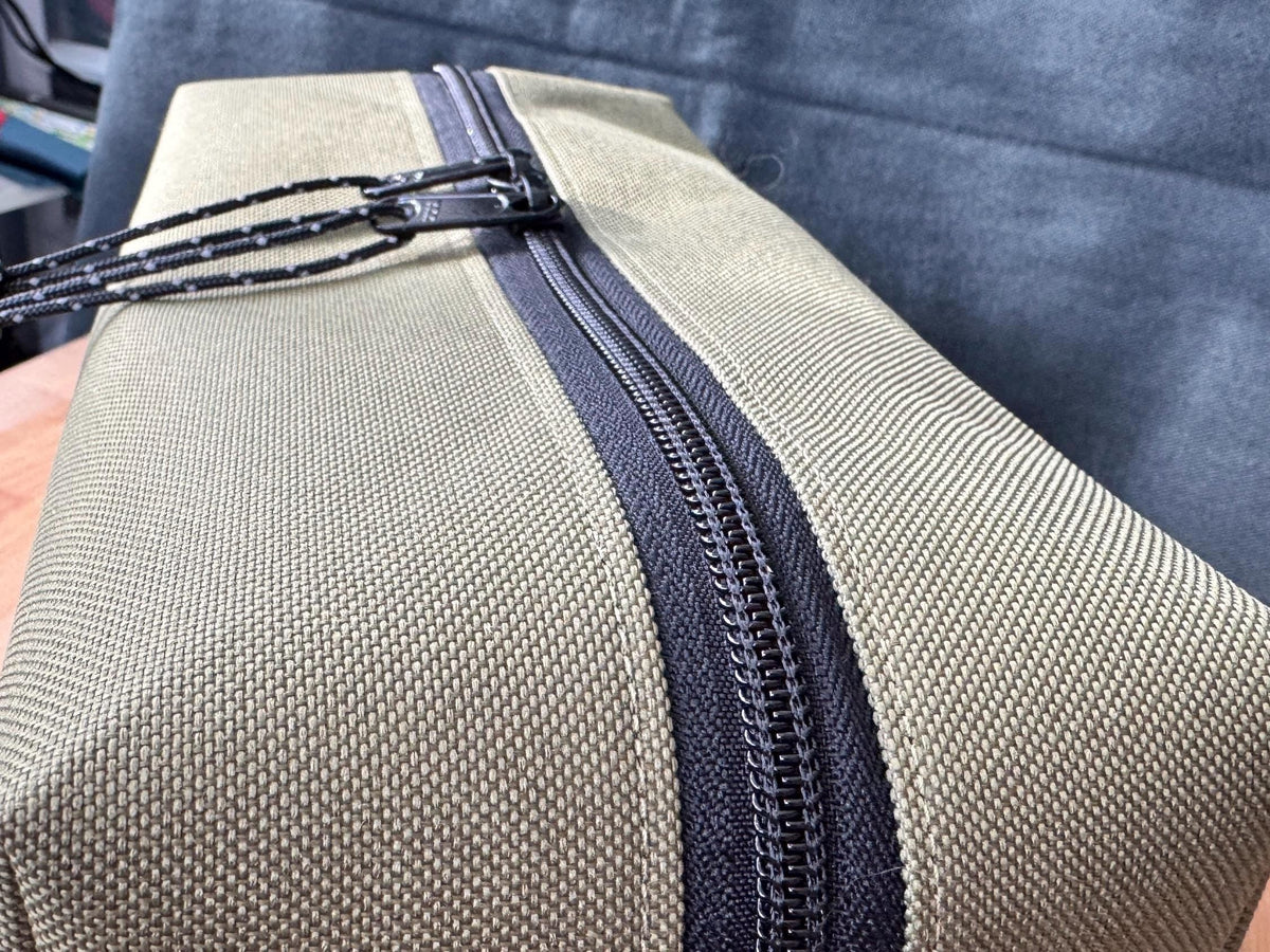 Close-up of a beige bag with a black zipper on a blue fabric background