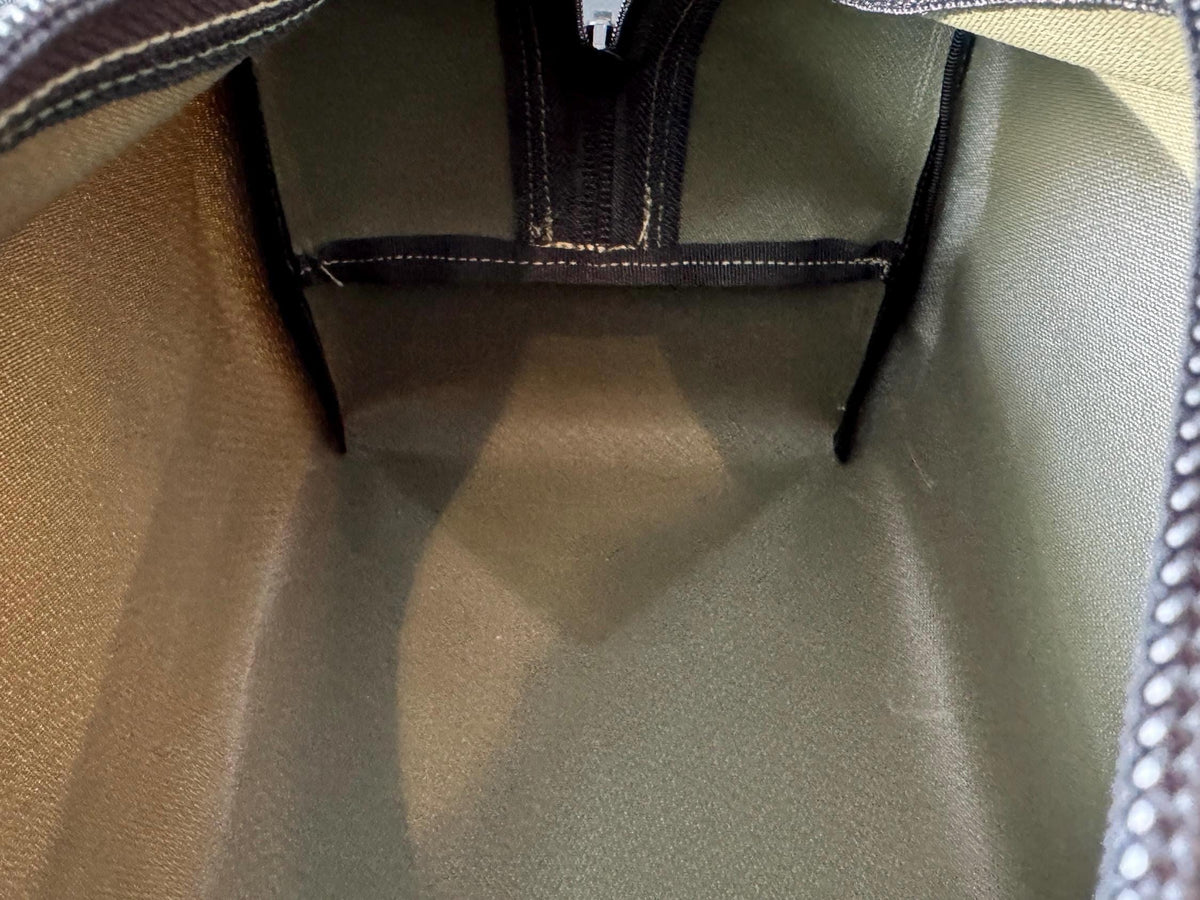 Close-up of a green bag with a zipper, showing fabric texture and stitching details.
