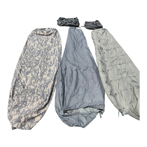 Three camouflage and solid-color sleeping bags laid out side by side on a white background, including two small matching accessories at the top.