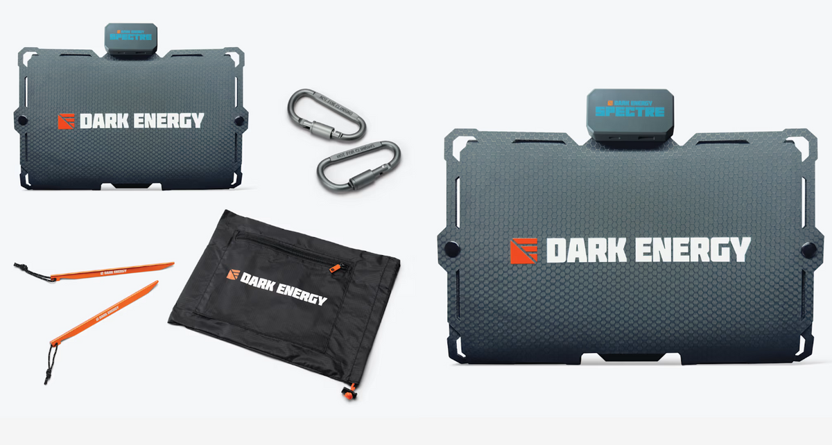 Dark Energy portable power system kit including a textured black rectangular battery pack with a Spectra brand top module, two silver carabiners, an orange and black carrying pouch, and two orange tools, all arranged on a light gray background.